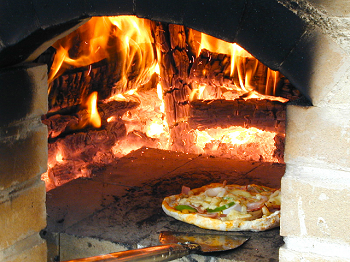 窯でピザを焼いている画像