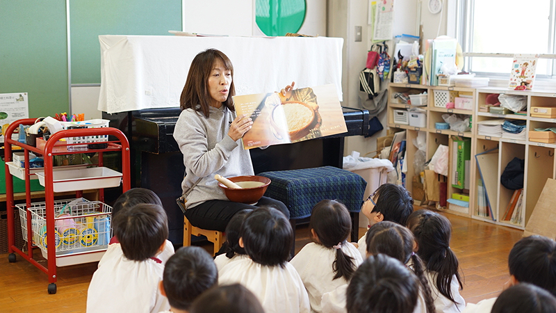 園児に読み聞かせをする保育士の写真